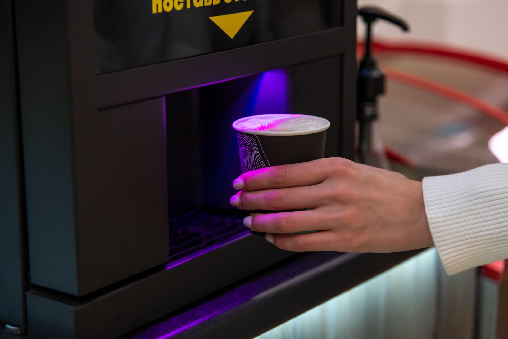 Woman taking coffee cup from coffee machine