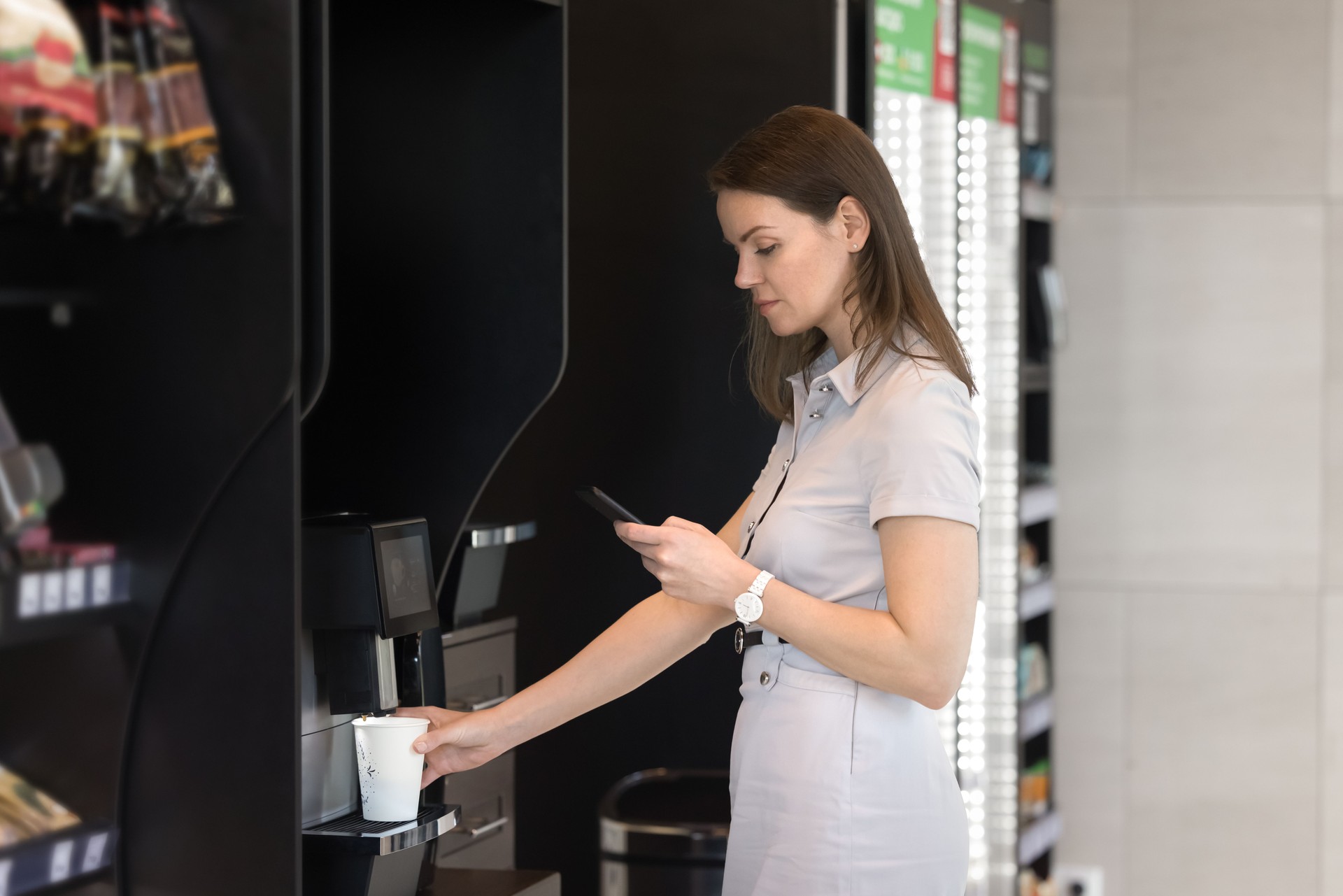 Modern office employee woman using coffee vending machine