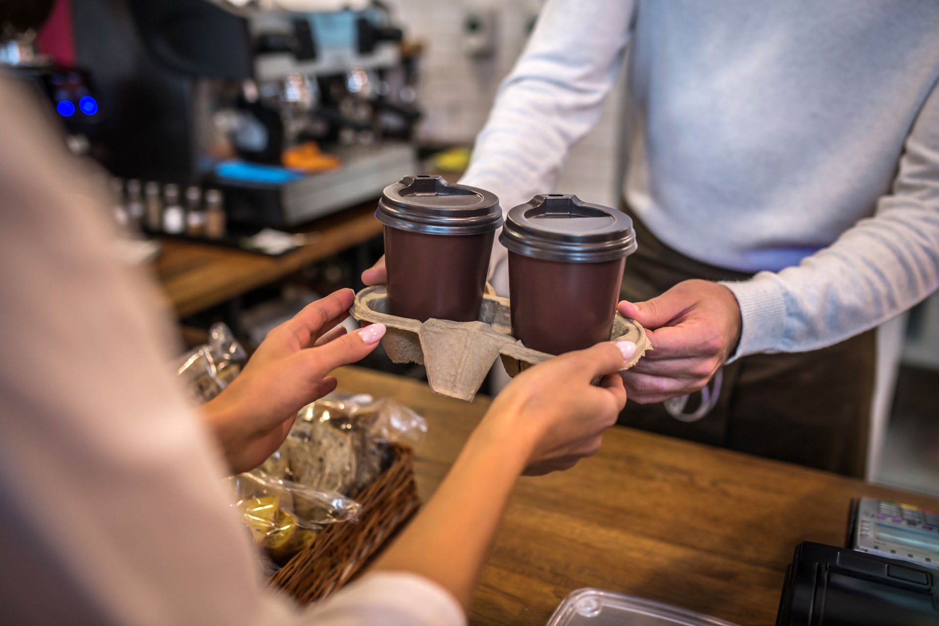 Close up of cashier passing two cups of coffee to the customer